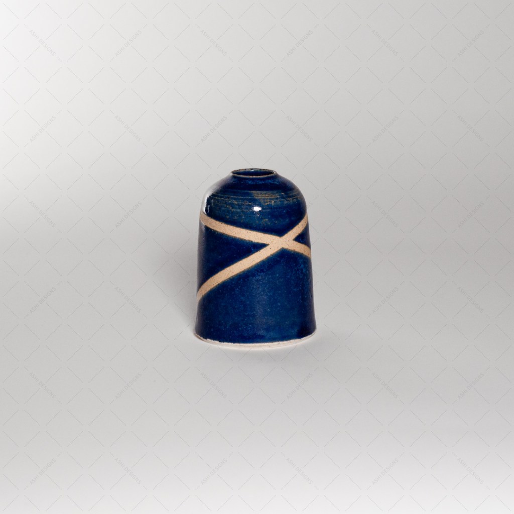A dark blue bud vase with two white lines crossing, making an X.