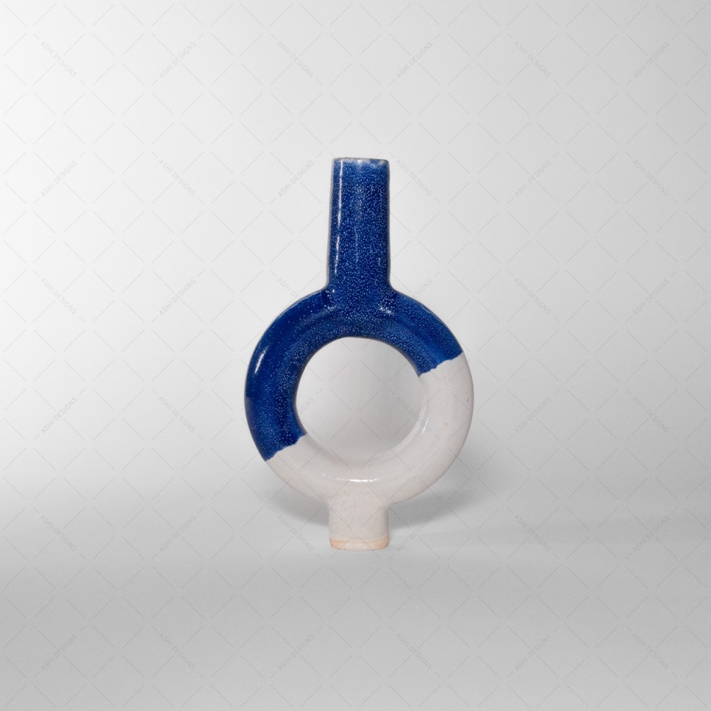 A vase shaped like a ring with cylinders extending from the top and bottom. Its lower half is glazed in white and its upper half is glazed in cobalt blue.