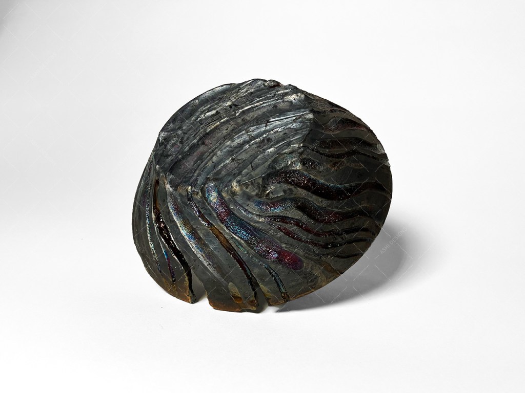 Underside of the carved bowl, which has a matte black surface and shiny multicolor details.