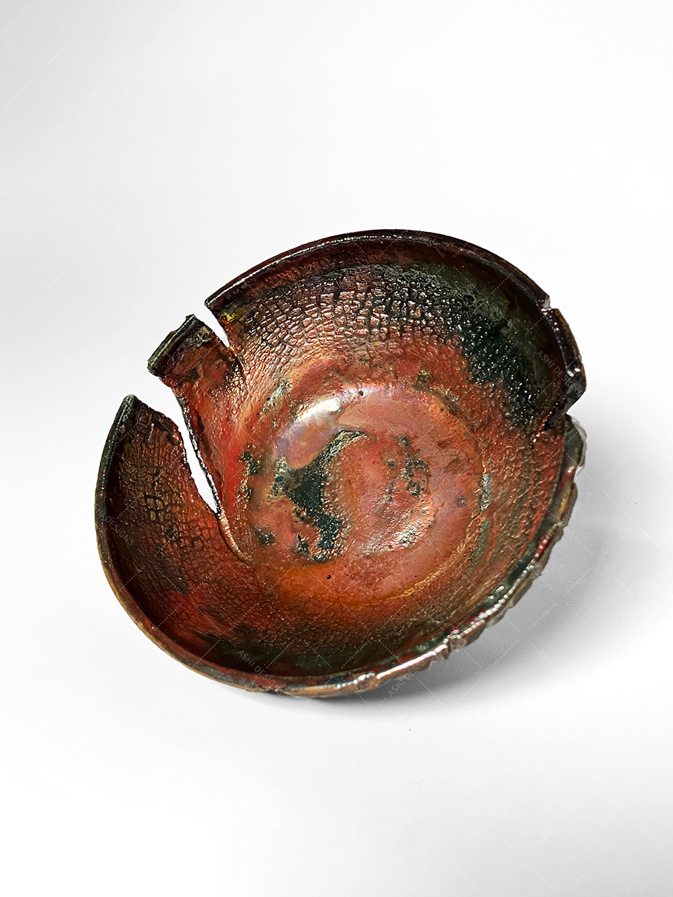 Interior of the carved bowl, glazed in shiny copper. Large cuts have been made into the walls of the dish.