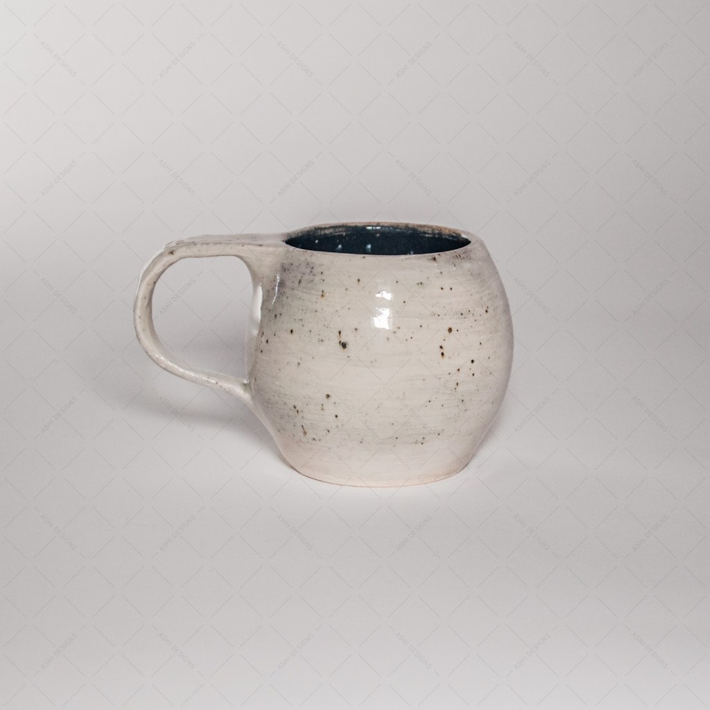 A white, spherical mug with speckles and a black interior.