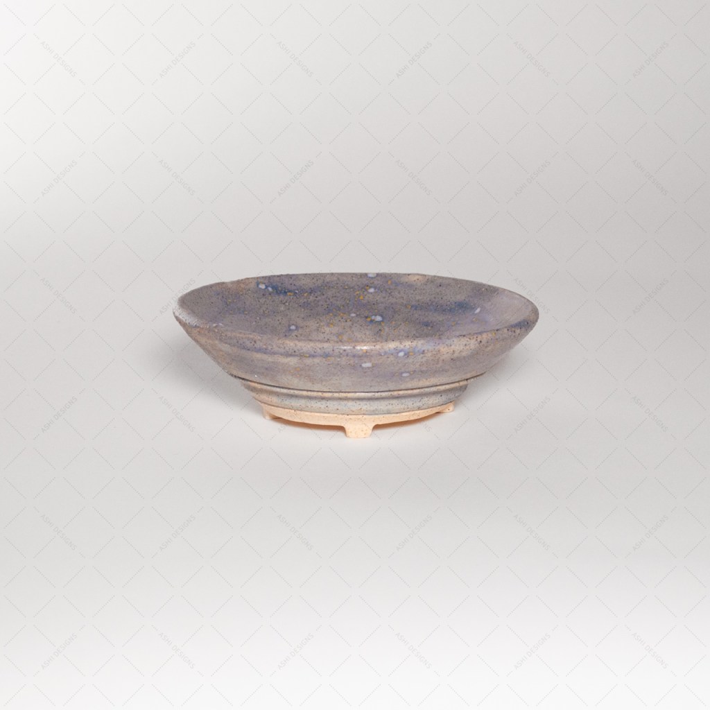 A speckled periwinkle dish with a carved base and four small feet.