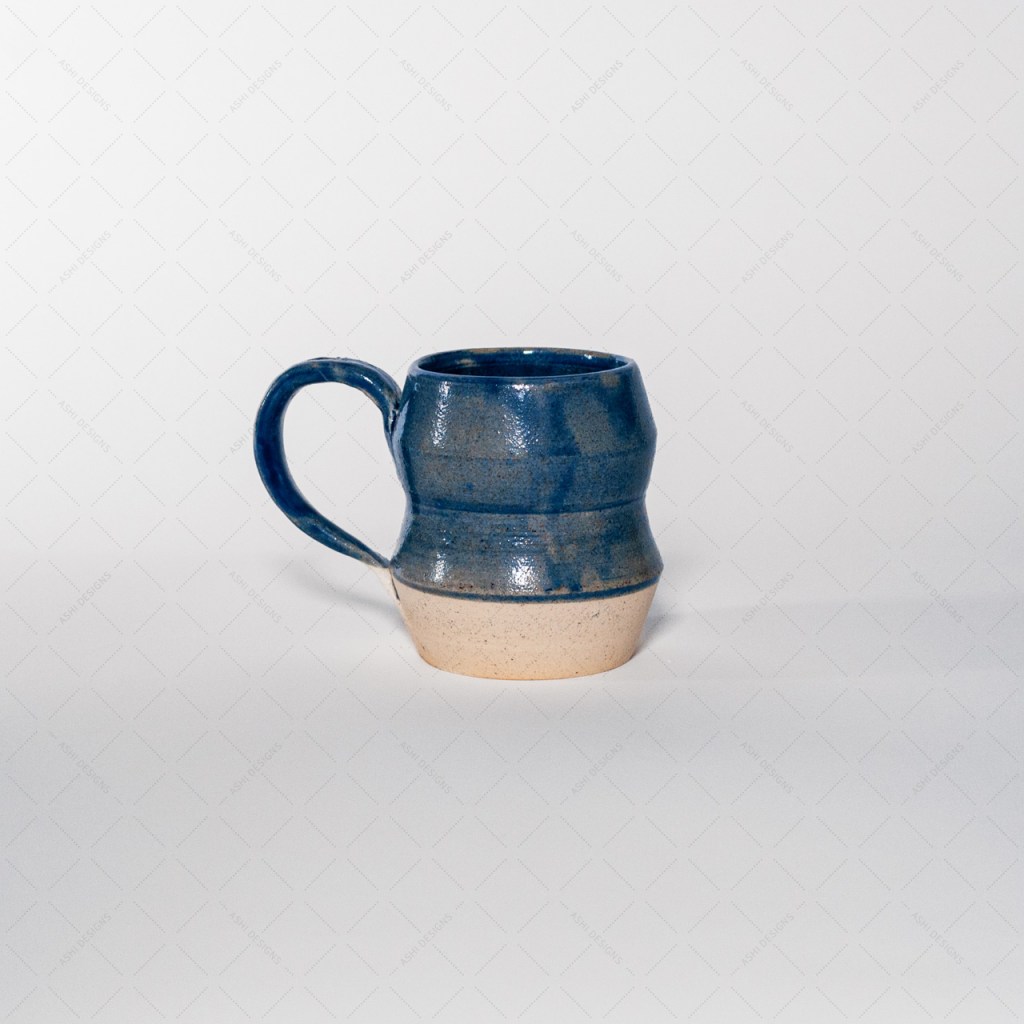 A mug with an angular profile and tapered waist, glazed with a translucent cobalt blue on the top 3 quarters.